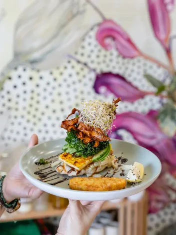 Lifestyle food photography of plated vegan corn fritters being served at a Brisbane vegan cafe